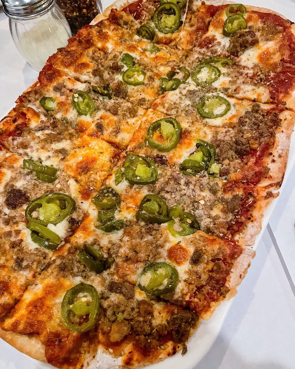 Thin-crust pizza, half sausage, half jalapeño